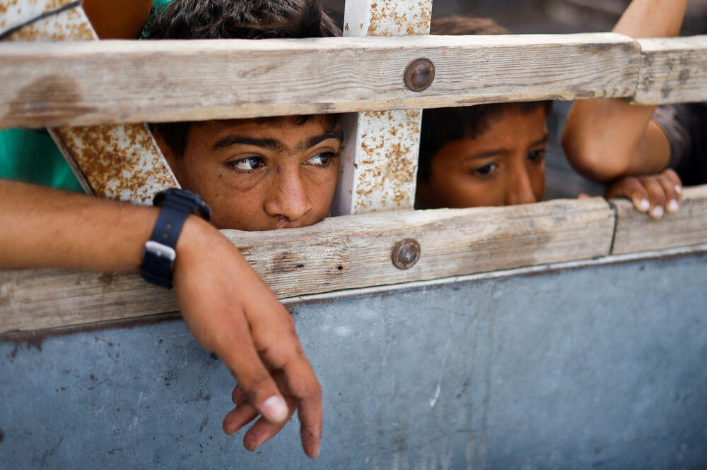 Djeca tokom sahrane u Rafi u južnom pojasu Gaze gledaju u vozilo koje nosi tijela Palestinaca ubijenih u izraelskom napadu na područje namijenjeno raseljenim osobama, Foto: Reuters