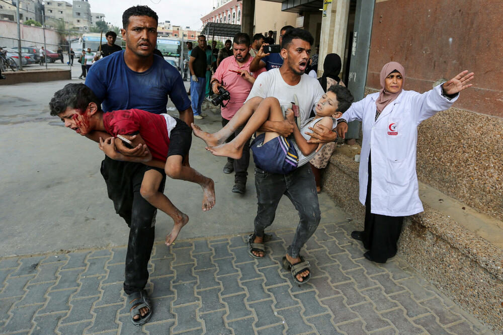 Ljudi nose ranjenu palestinsku djecu nakon bombardovanja u bolnicu