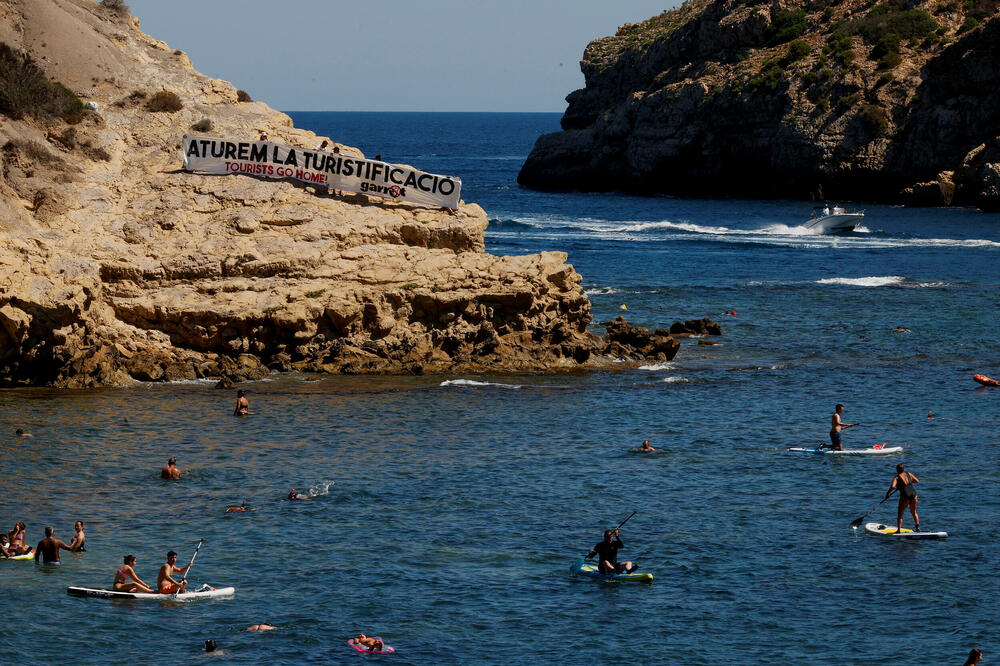 Natpis “Protiv turistifikacije! Turisti, idite kući!” na plaži u Španiji